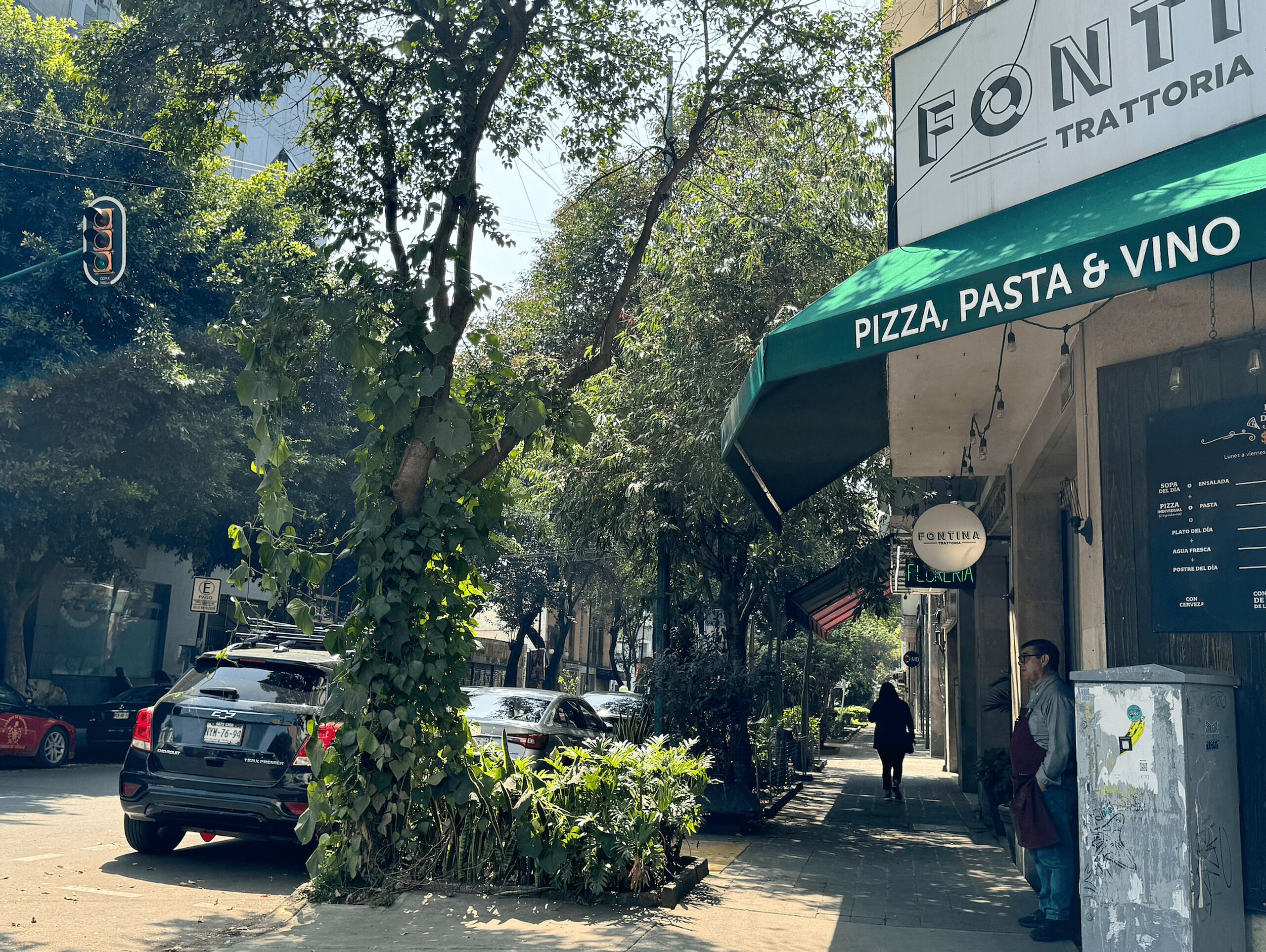 Una veduta di strada con un ristorante chiamato 'Fontina Trattoria' che offre pizza, pasta e vino.