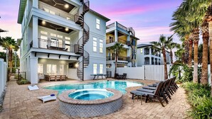 Un edificio de varios pisos con piscina, mobiliario exterior y palmeras.