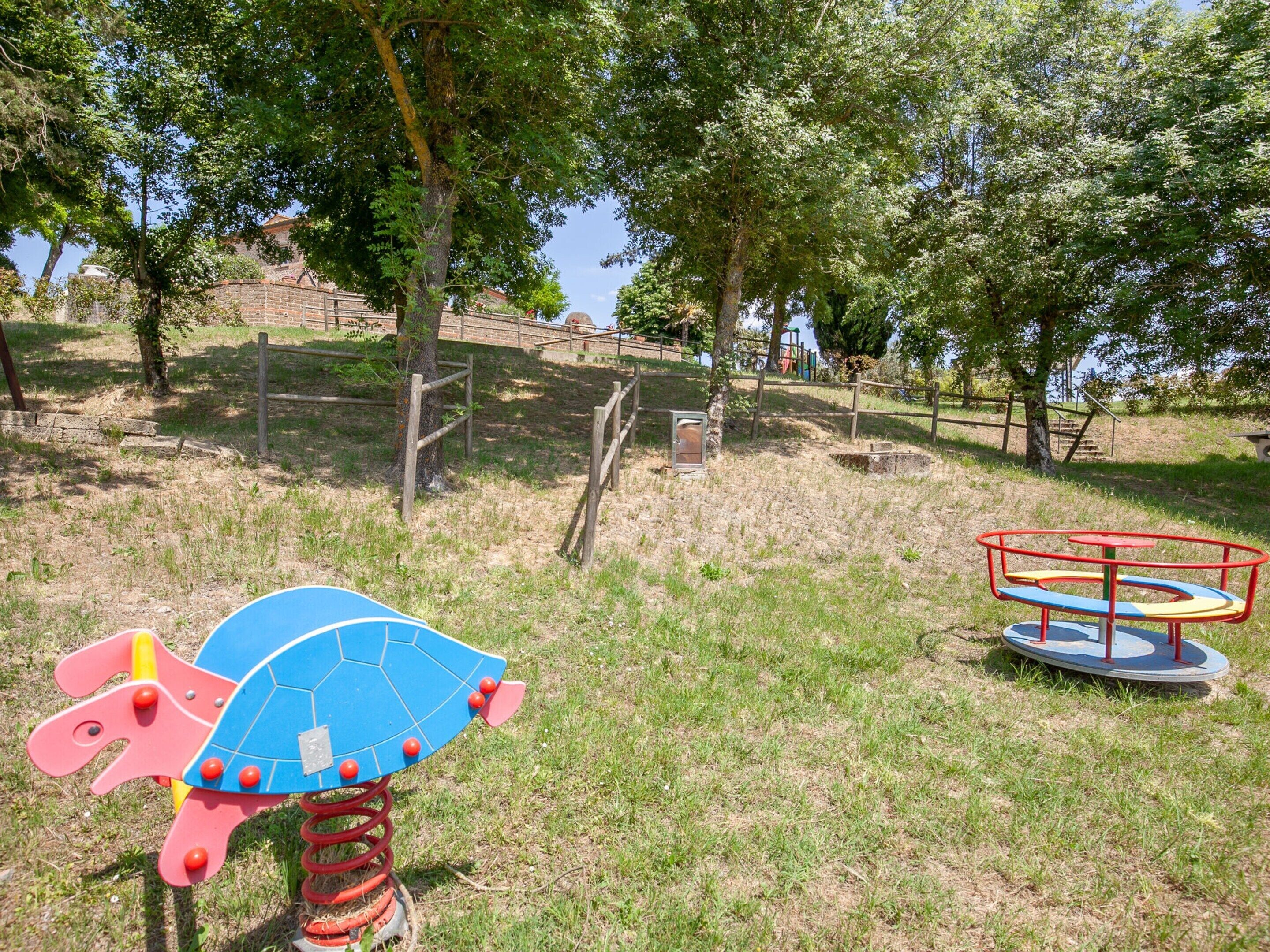 Une aire de jeux avec un toboggan, une balançoire et un manège.