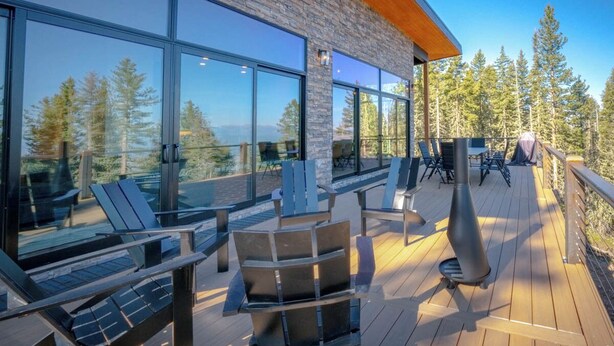 A deck with outdoor seating and a view of trees and mountains.