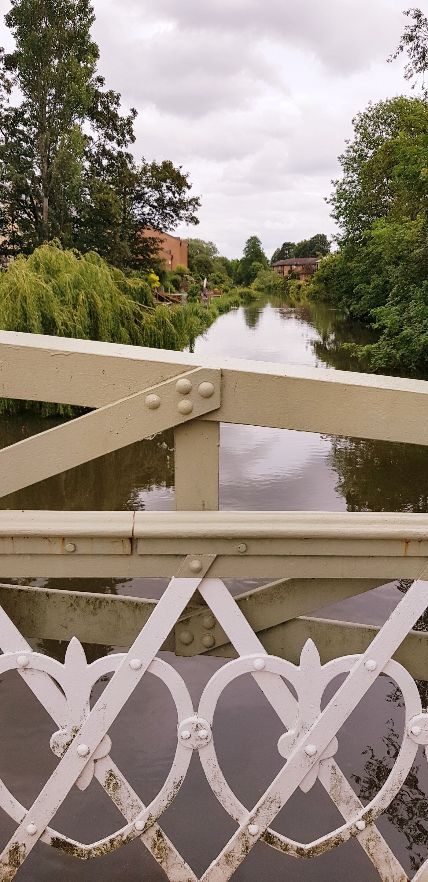 Un puente con barandilla de metal y un río debajo.