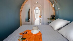A bedroom with a bed, a mirror, a nightstand, and a view of another room. - Premium Tent Lodge for Family (Tarragona)