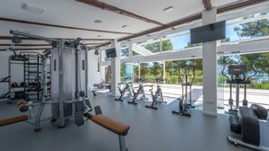 A spacious gym with various exercise equipment, large windows, and a bench. - Premium Tent Lodge for Family (Tarragona)