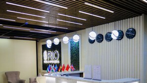 A reception area with a modern design, featuring a reception desk, chairs, and a wall with clocks and flags. - Rio Hotel (Samarkand)