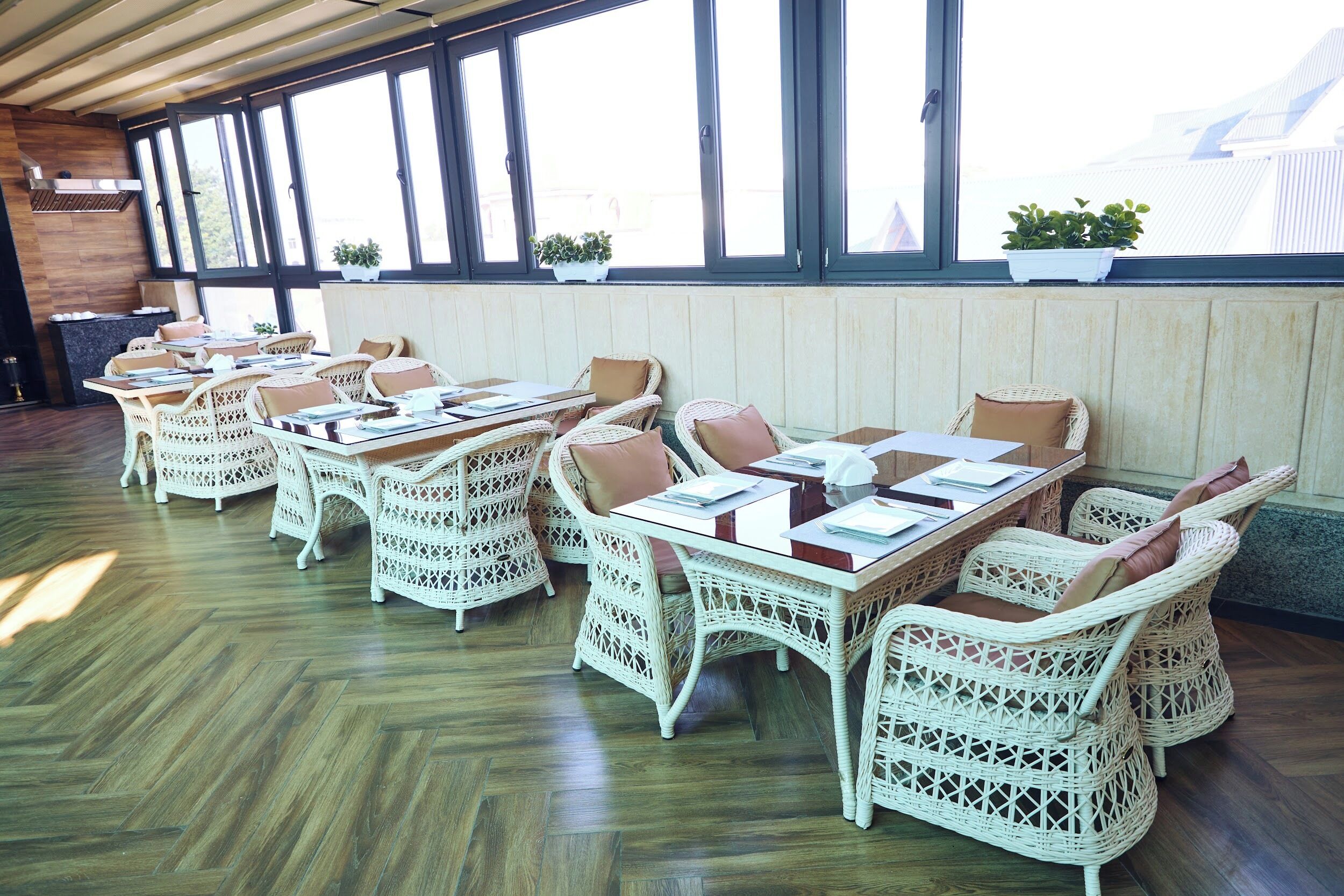Un restaurante con mobiliario de mimbre y ventanas amplias.