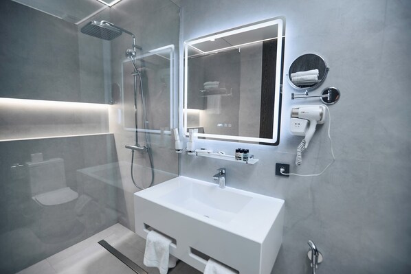 A modern bathroom with a glass-enclosed shower, a large mirror, a white sink, and a towel rack. - Rio Hotel (Samarkand)