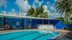 A swimming pool with lounge chairs and a mural on the wall. - HOTEL EL PIRATA MORGAN (Providencia)