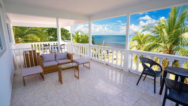 A balcony with a view of the ocean, furnished with a sofa, chairs, and a table. - HOTEL EL PIRATA MORGAN (Providencia)