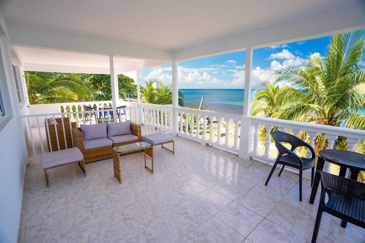Varanda com vista para o oceano, mobiliada com sofá, cadeiras e mesa.