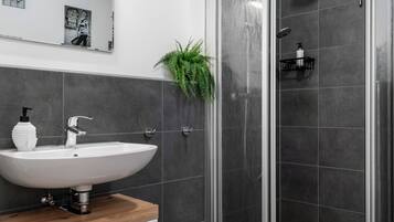 A modern bathroom with a white sink, wooden countertop, and a shower with a glass door.
