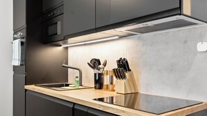 A modern kitchen with a stainless steel sink, a built-in oven, and a wooden countertop. - Design luxury, fully equipped, 30min Leipzig Hbf 8 (Schkeuditz)