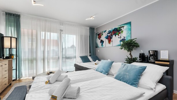 A modern hotel room with two beds, a large window with sheer curtains, a world map artwork, a coffee machine, and a desk with a lamp. - Design luxury, fully equipped, 30min Leipzig Hbf 8 (Schkeuditz)