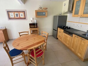 Cozy kitchen area with a dining table and chairs, microwave, refrigerator, and sink.