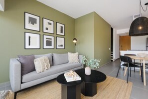 Ein modernes Wohnzimmer mit einem grauen Sofa, einem runden schwarzen Couchtisch und gerahmten Kunstwerken an der Wand.