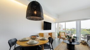 A modern dining area with a round table, black chairs, a woven pendant light, and a view of the city through large windows. - Modern 2BR Duplex, with balcony. (Ciudad de México)