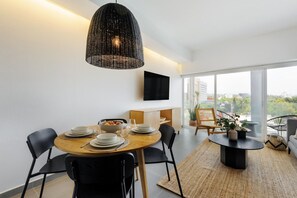 A modern dining area with a round table, black chairs, a woven pendant light, and a view of the city through large windows. - Modern 2BR Duplex, with balcony. (Ciudad de México)