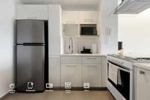 A modern kitchen with a refrigerator, microwave, coffee maker, and stove.