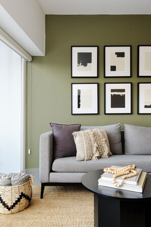 Ein modernes Wohnzimmer mit einem grauen Sofa, einem schwarzen Couchtisch und einem gewebten Korb.