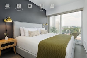 A modern bedroom with a large bed, bedside lamps, a view of the city through a large window, and a balcony. - Modern 2BR Duplex, with balcony. (Ciudad de México)