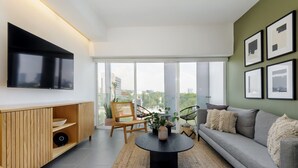 A modern living room with a large flat-screen TV, a grey sofa, and a wooden entertainment unit. - Modern 2BR Duplex, with balcony. (Ciudad de México)
