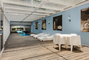 A covered outdoor area with a pool, white lounge chairs, and a table with chairs. - Modern 2BR Duplex, with balcony. (Ciudad de México)