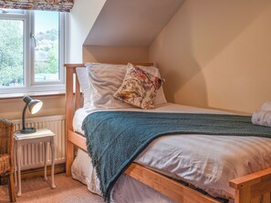 Une chambre confortable avec un lit en bois, une petite table de chevet avec une lampe et une fenêtre donnant sur un paysage verdoyant.
