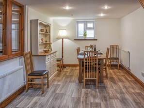 A dining area with a wooden table, chairs, a lamp, and a window.