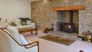 Una sala de estar acogedora con pared de piedra, chimenea, sofá y una mesa de centro.