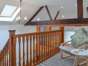 A wooden staircase with a glass ceiling, a cushioned chair with a floral pillow, and a small table with two coasters. - 3 bedroom accommodation in Lydney (Lydney)