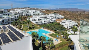 Ett modernt semesterkomplex med flera vita byggnader, en swimmingpool och solpaneler.