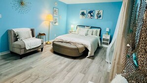 Un dormitorio con cama, sofá, una mesita y un adorno en la pared.