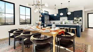 Una cocina moderna con armarios oscuros, una isla central e iluminación colgante.