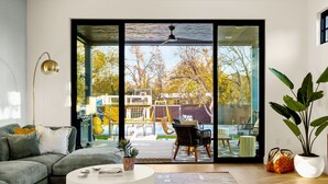 Una sala de estar moderna con un amplio ventanal corredera que da a un patio exterior.
