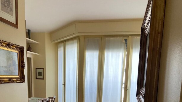 A spacious room with wooden flooring, a dining area with a table and chairs, and large windows with curtains. - Suite51 - Cozy apartment in Porta Romana near the center (Milano)