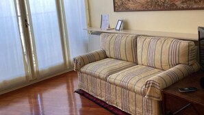 A living room with a striped sofa, a painting on the wall, and a sliding glass door. - Suite51 - Cozy apartment in Porta Romana near the center (Milano)