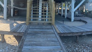 Una terraza de madera que conduce a un edificio moderno con fachada de vidrio y un balcón.
