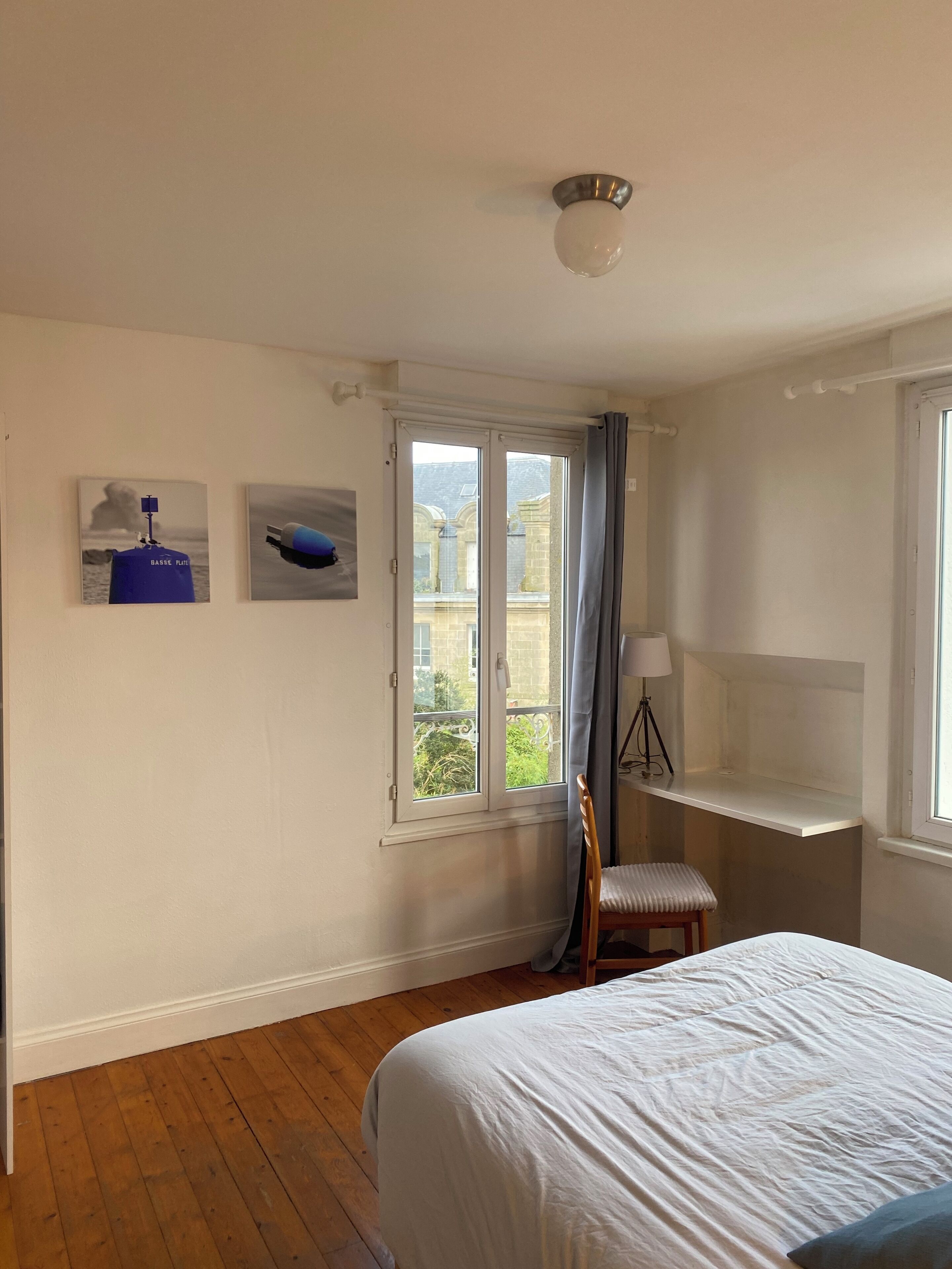 A bedroom with a bed, a chair, a desk, and a window with curtains.