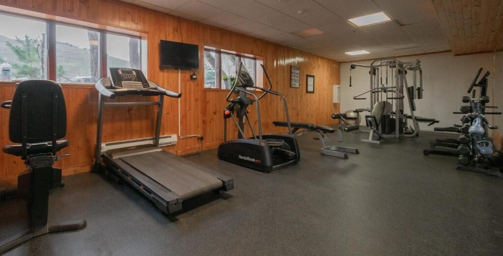 Un gimnasio con cintas de correr, elípticas y máquinas de pesas.