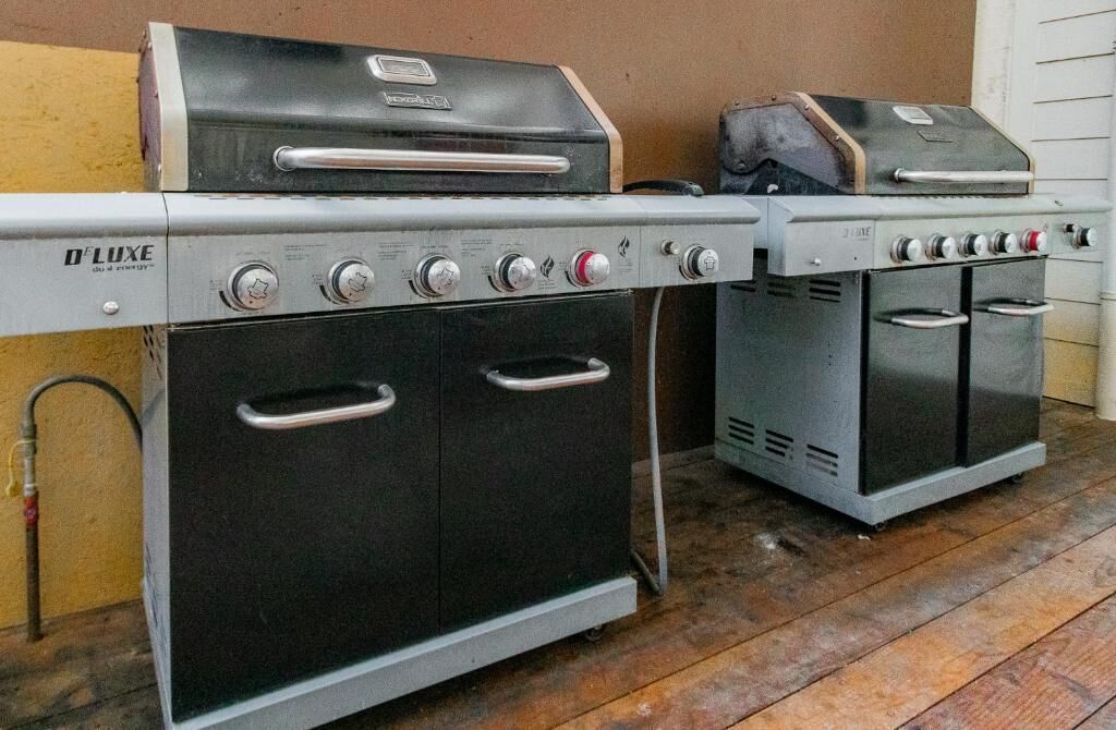A portable gas grill and oven set up on a wooden deck.