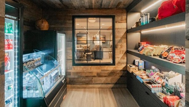 A narrow hallway with a wooden wall, a glass display case, and shelves with snacks.