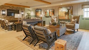 A spacious living room with a stone fireplace, comfortable seating, and artwork on the walls.