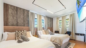 Habitación de hotel con dos camas, un ventanal grande, un televisor de pantalla plana y un cabecero de madera.
