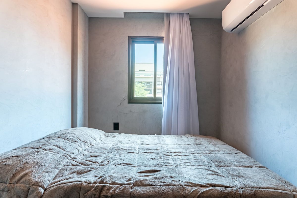Une chambre à coucher avec un lit, une fenêtre et un appareil de climatisation.