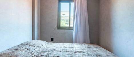 A bedroom with a bed, a window, and an air conditioning unit.