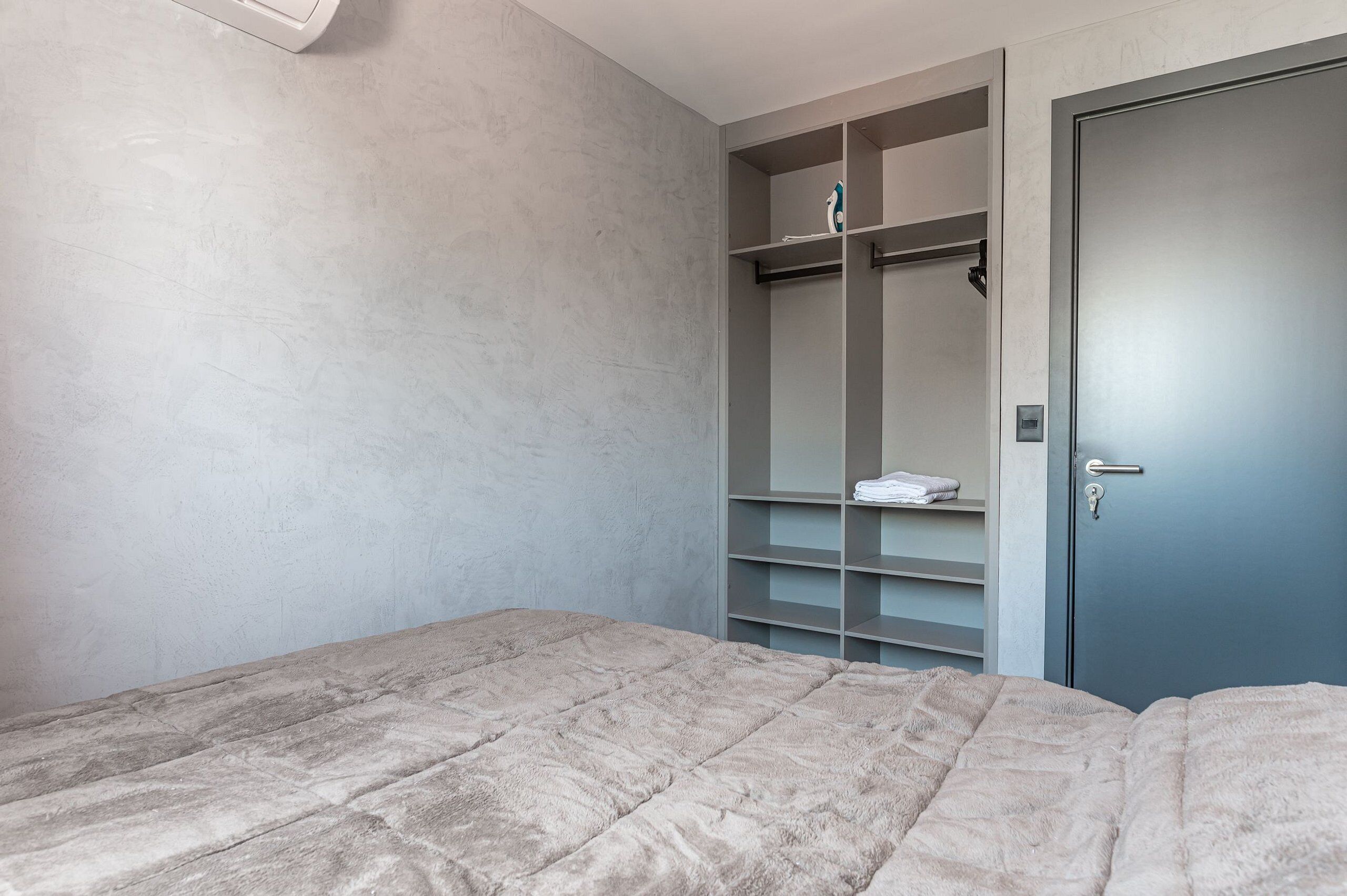 A bedroom with a bed, a wardrobe, and a door.