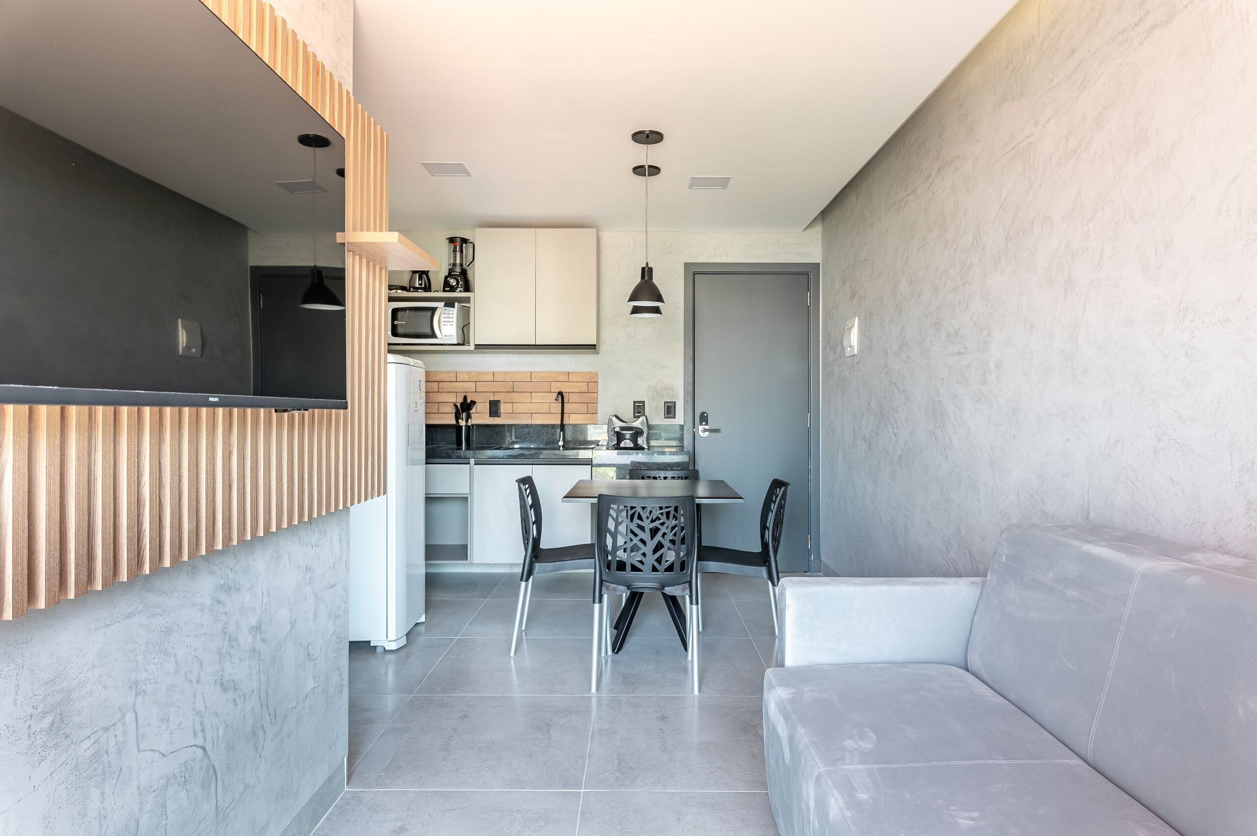 A modern kitchen with a dining area, featuring a built-in oven, microwave, and a coffee machine.