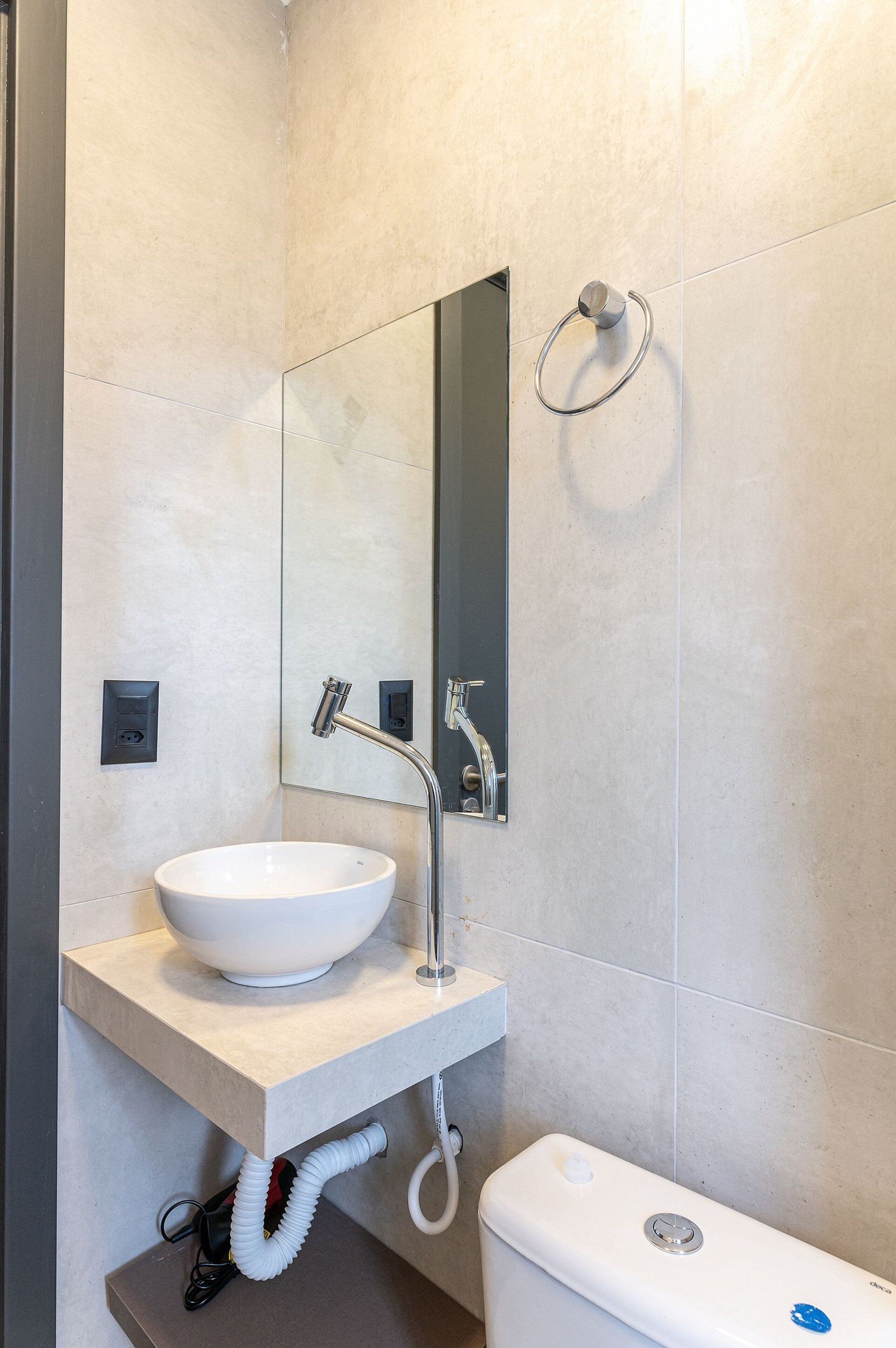 Un bagno moderno con un lavandino bianco, uno specchio e un water.