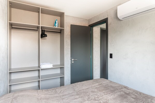 Une chambre à coucher avec un lit, une armoire grise et une porte.