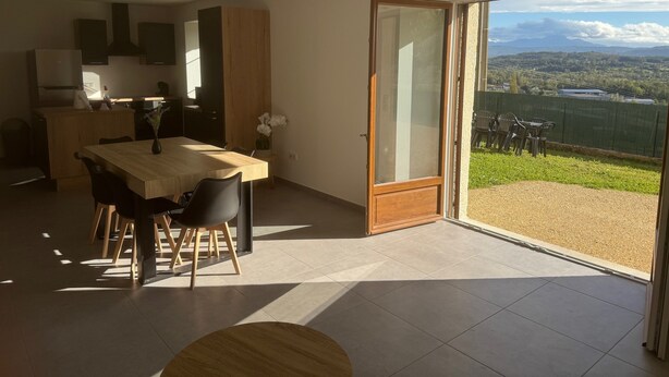 Eine moderne Küche mit Essbereich, große Schiebeglasfenster zu einem Balkon mit Blick auf die Landschaft.