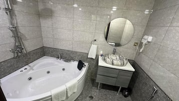 Een aparte badkuip en douche, een haardroger, handdoeken, zeep